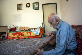 علی پیرمرد ۹۲ ساله عاشیقلار روستای زرگر در حال نوازیدن و خواندن ترانه‌ای آذری برای میهمانانش.